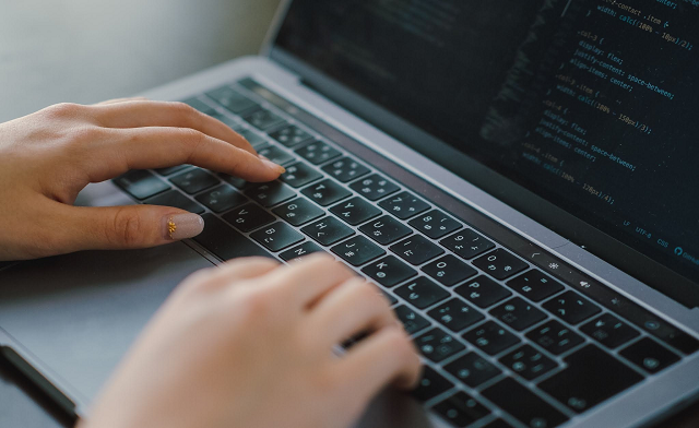 ノートパソコンでプログラミングをする女性の手